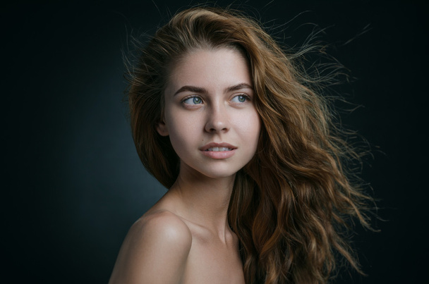 Dramatic portrait of a girl theme: portrait of a beautiful girl with flying hair in the wind against a background in studio - Foto, Imagem