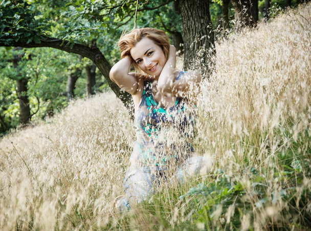 Mooie jonge Kaukasische brunette houdt haar in de natuur - Foto, afbeelding