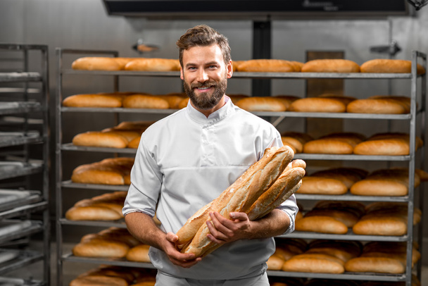 Bäcker hält Baguette in der Manufaktur - Foto, Bild