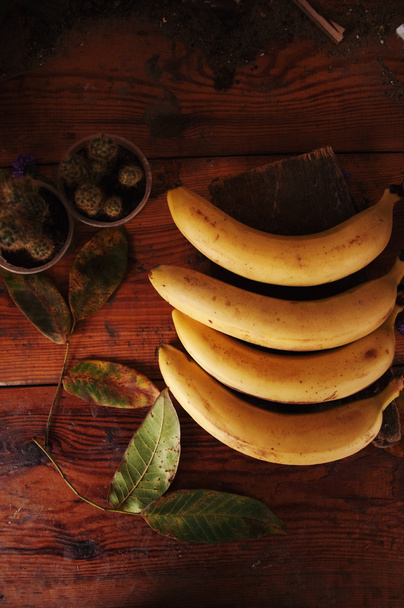 спелые желтые бананы в плетеной корзине, на деревянном фоне, вид
 - Фото, изображение