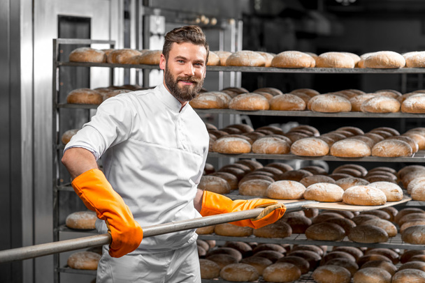 Fırıncı küreği ekmek ile koyarak, üretim loafs - Fotoğraf, Görsel