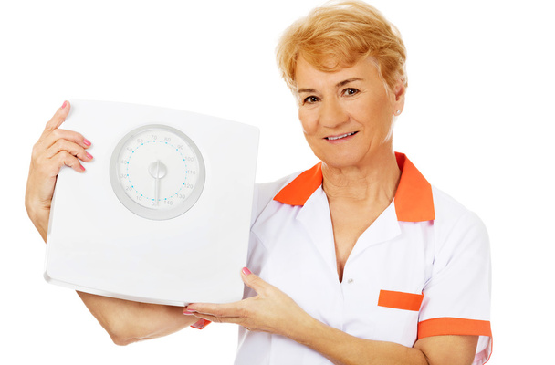 Smile elderly female doctor or nurse holds weigh scale - Fotó, kép
