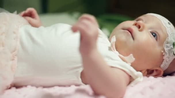 Ευτυχισμένο μωρό κορίτσι ξαπλωμένο στο ροζ κουβέρτα - Πλάνα, βίντεο