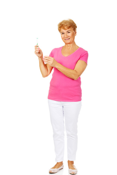 Smiling senior woman holding toothpaste and toothbrush - Photo, image
