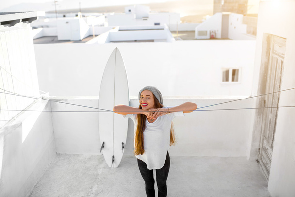 Woman with surfboard on the white city background - Foto, Bild