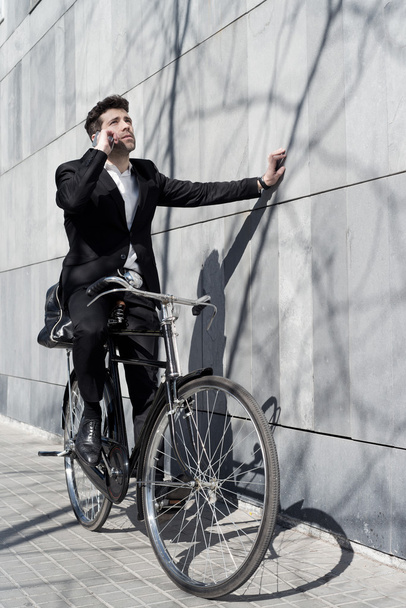 businessman speaks by telephone cycled looking up - Zdjęcie, obraz