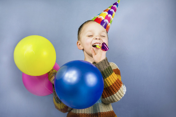 boy in a celebratory cap holding colorful balloons - Foto, imagen