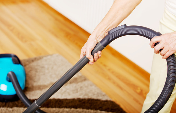 Senior woman vacuuming carpet at home - Zdjęcie, obraz