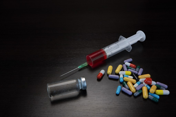 Pilules colorées, seringue et ampoule avec liquide sur Backgrou noir
 - Photo, image