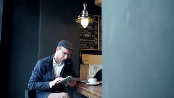 Young man using tablet computer in cafe - Materiał filmowy, wideo