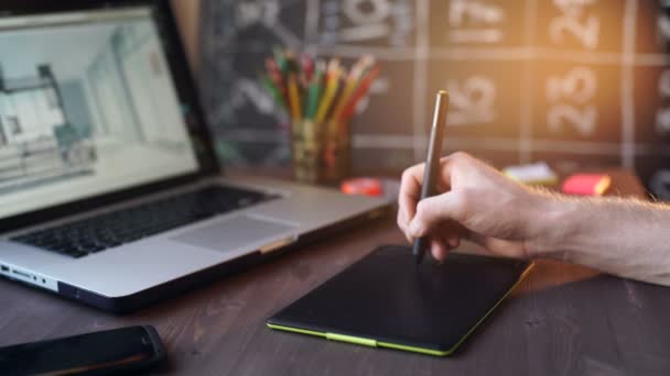 Δημιουργικός επιχειρηματίας που γράφει σε γραφικό tablet ενώ χρησιμοποιεί φορητό υπολογιστή στο γραφείο - Πλάνα, βίντεο