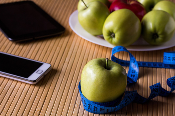Яблоки на тарелке на светлом бамбуковом столе. Рядом находится стол
 - Фото, изображение