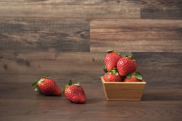 Fresh strawberries in a bamboo bowl on a wooden background - Foto, imagen