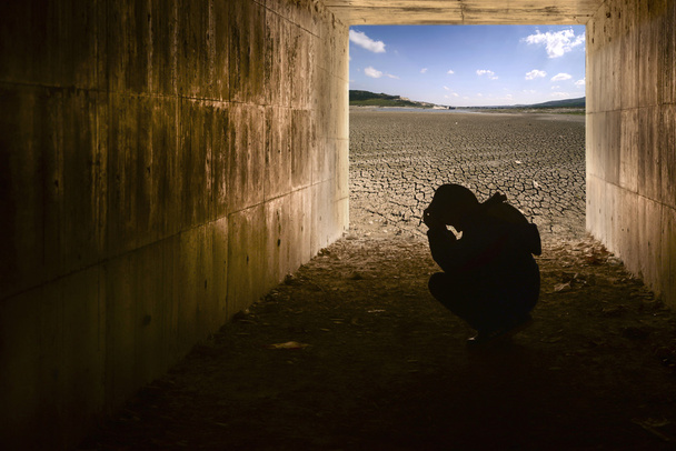 Kind in de tunnel en gebarsten bodem achtergrond met blauwe lucht - Foto, afbeelding
