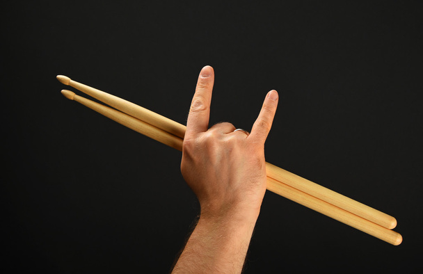 Рука людини з барабанними паличками і диявольськими рогами над чорним
 - Фото, зображення