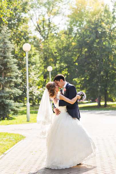 couple de mariage câlin, la mariée tenant un bouquet de fleurs, marié embrassant son
 - Photo, image
