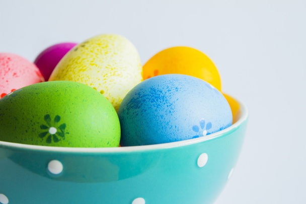Oeufs de Pâques colorés dans un bol vert tacheté sur fond clair
 - Photo, image
