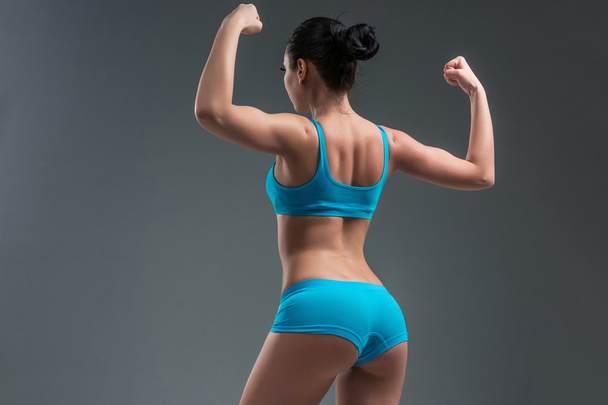atletische meisje toont spieren - Foto, afbeelding