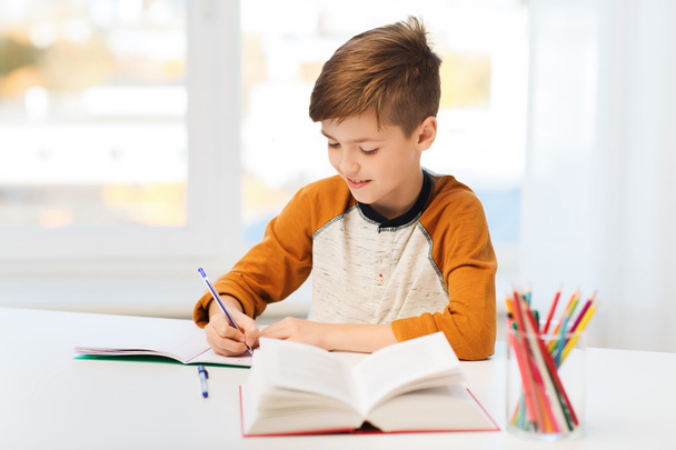 smiling student boy writing to notebook at home - Valokuva, kuva