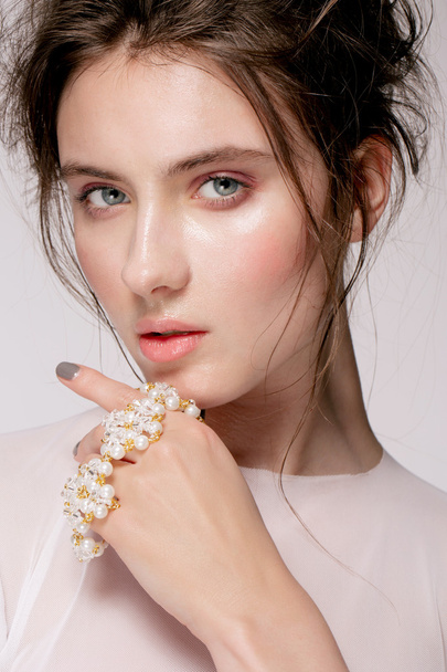 Portrait of young beautiful woman with natural beauty, nude makeup, bridal hairstyle and jewellery - 写真・画像