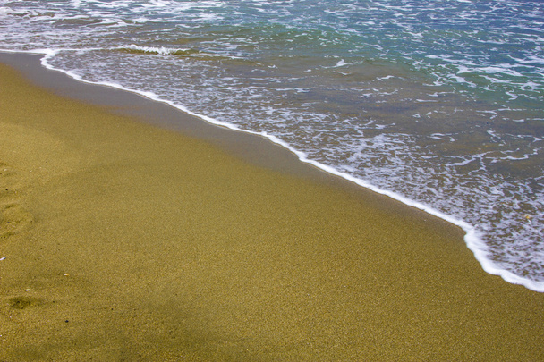 Ola de mar sobre arena dorada de playa al atardecer
 - Foto, imagen