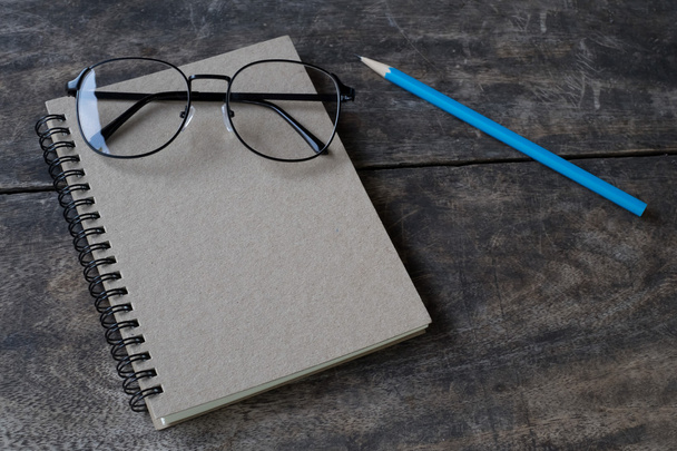 libreta blanca de naturaleza muerta, lápiz y gafas en un escritorio
 - Foto, Imagen