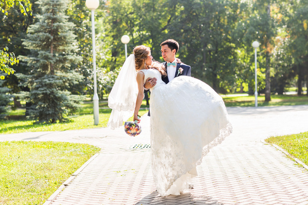 весільна пара обіймає, наречена тримає букет квітів, наречений обіймає її
 - Фото, зображення