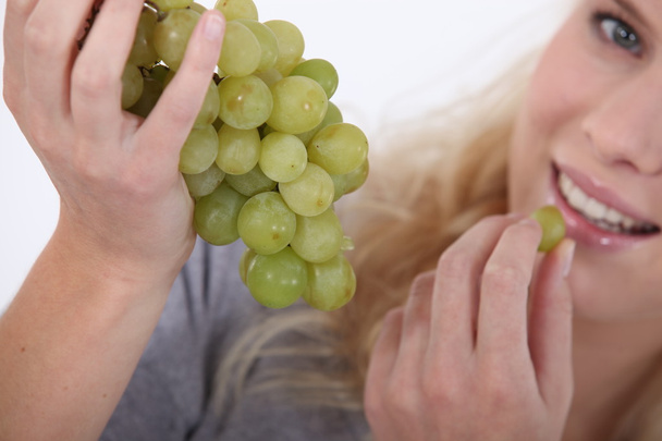 Attractive blond woman eating bunch of grapes - Foto, Bild