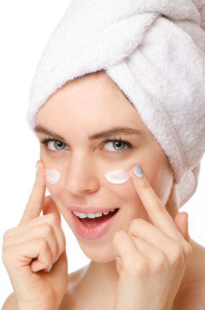 mooie jonge vrouw toepassing van een crème op haar gezicht geïsoleerd op witte achtergrond - Foto, afbeelding