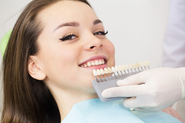 Close up portrait of Young women in dentist chair, Check and select the color of the teeth. Dentist makes the process of treatment in dental clinic office - 写真・画像