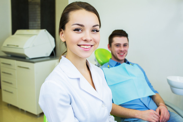 Dental surgeon and patient smiling happy after dental checkup, looking at camera. - Foto, Imagem