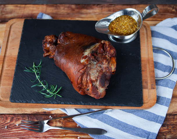 Baked pork shank, rosemary branch and honey sause on a wooden ta - Photo, Image