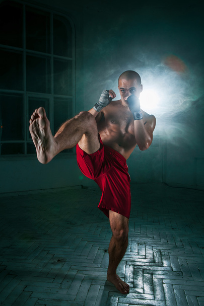 The young man kickboxing in blue smoke - Foto, afbeelding