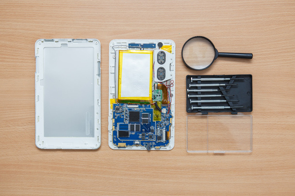disassembled tablet and tools on the table. View from above. - Foto, Bild