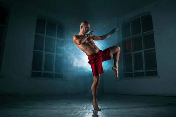 The young man kickboxing in blue smoke - 写真・画像
