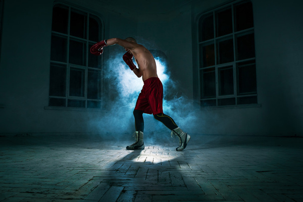Ο νεαρός άνδρας kickboxing στον μπλε καπνό - Φωτογραφία, εικόνα