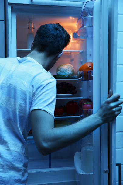 Homme à la recherche de nourriture au réfrigérateur la nuit
 - Photo, image