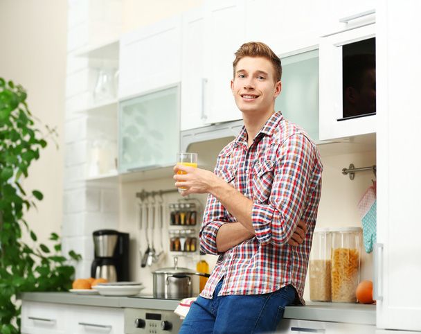 Handsome man with juice in kitchen - Foto, Imagem