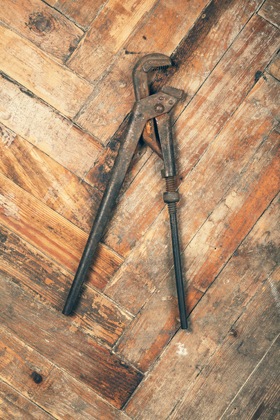 Pipe wrench on wooden floor - Fotó, kép