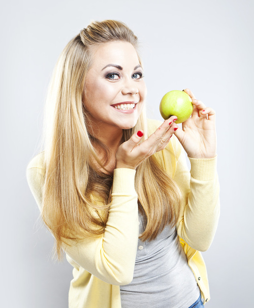 Χαμογελαστό κορίτσι με πράσινο μήλο. Πλατύ χαμόγελο. Υγιή δόντια - Φωτογραφία, εικόνα
