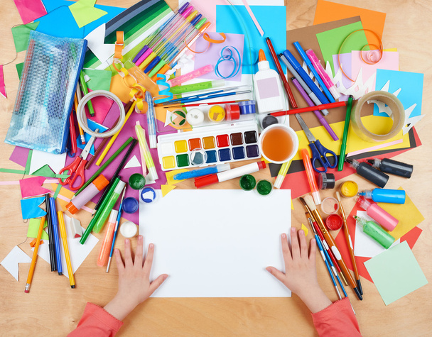 Ребёнок рисует вид сверху. Рабочее место с творческими аксессуарами. Плоские инструменты для рисования
. - Фото, изображение