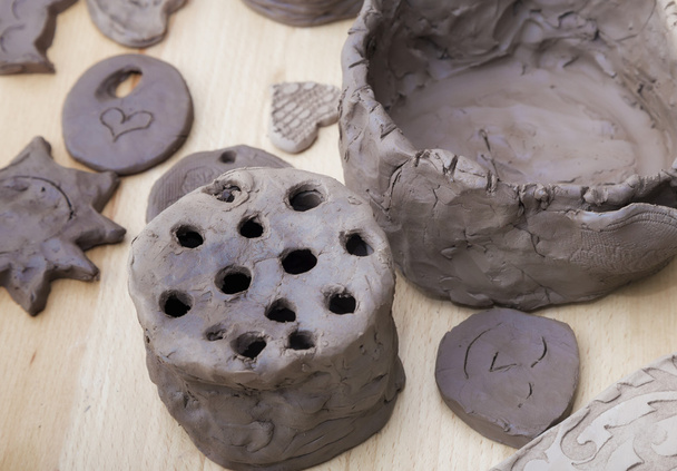 Many amateur handmade unbaked clay moldings on a wooden table - Fotoğraf, Görsel