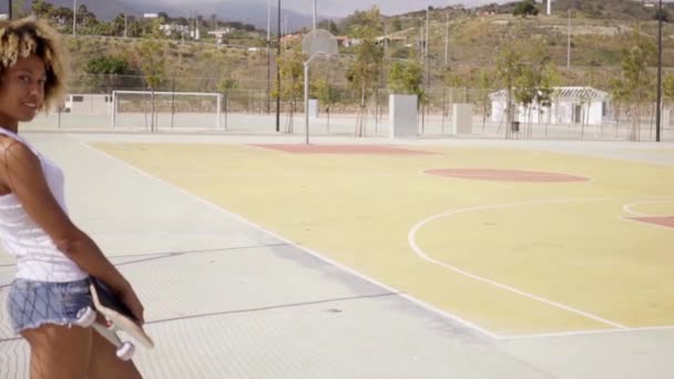 женщина, стоящая со скейтбордом на баскетбольной площадке
 - Кадры, видео