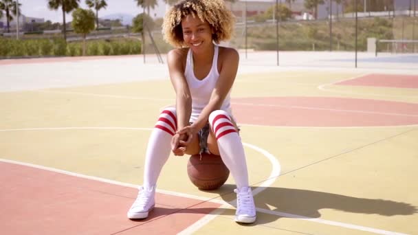 woman sitting on a basketball ball at court - Metraje, vídeo