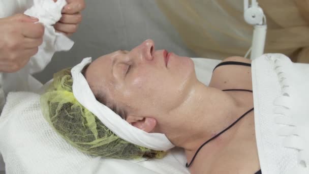 Cosmetólogo limpie la cara de la mujer en el salón limpiando la servilleta. Cuidado anti edad
 - Metraje, vídeo