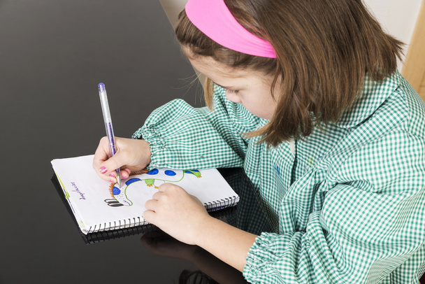 Κοριτσάκι να σύρει ένα δεινόσαυρο σε ένα σημειωματάριο - Φωτογραφία, εικόνα