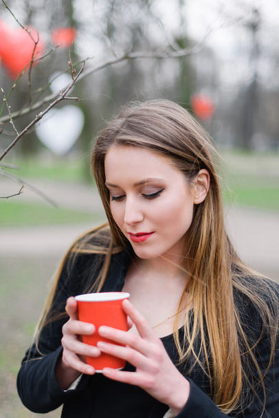 Portrait of young beautiful stylish girl drinking coffee in the park - Foto, Bild