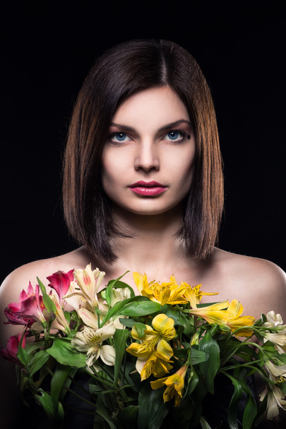 young brunette girl keeps flowers on black background - Фото, изображение