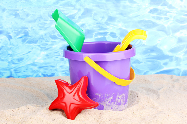 Childrens beach toys on sand on water background - Foto, afbeelding