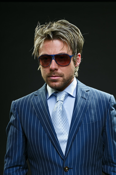Elegante hombre de negocios con pelo rubio corto con traje de rayas azules y corbata azul claro
. - Foto, imagen